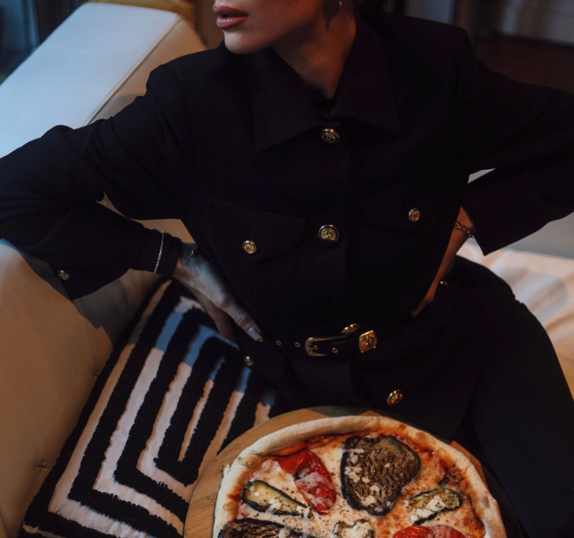 femme en noir avec une pizza sur les genoux
