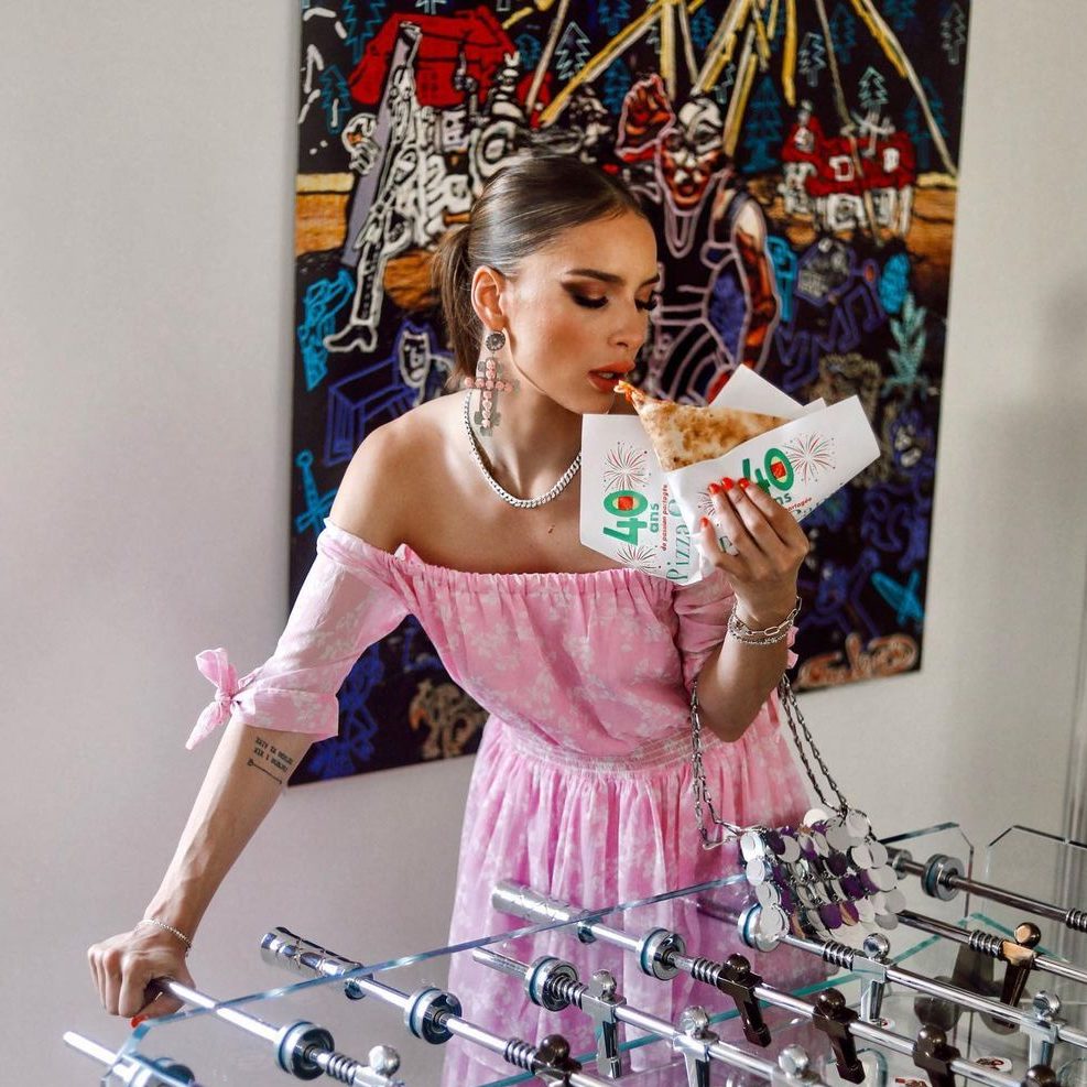 Fille en rose qui savoure une pizza