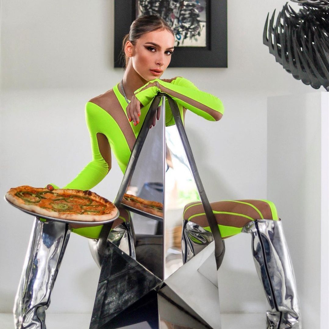Fille qui mets en avant une pizza en étant assise en habille fluo