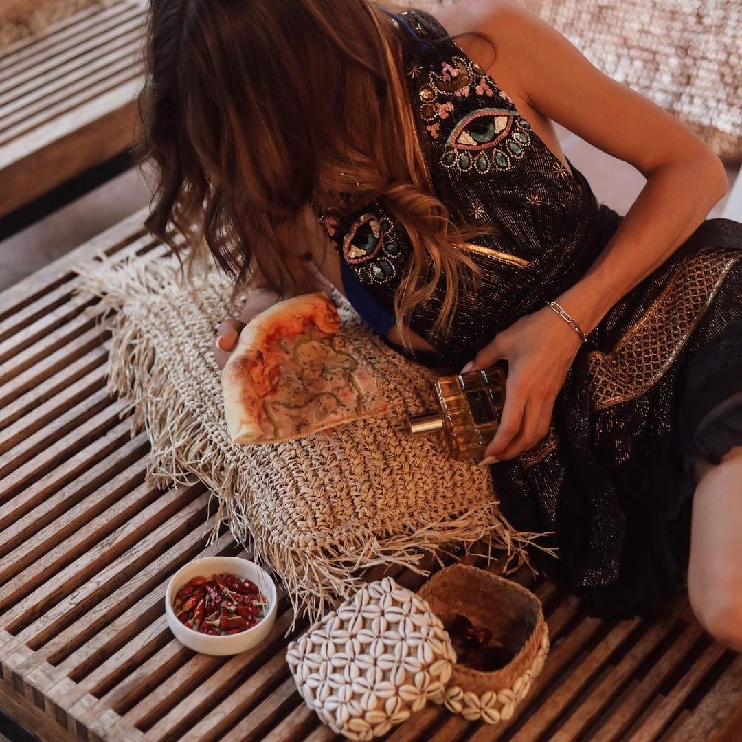 Fille sur un transat avec une part de pizza à la main